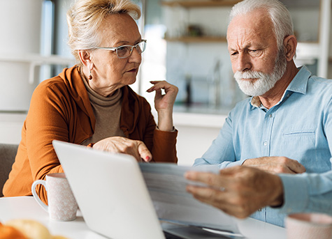 an older couple sit at a table reviewing trust fund information over coffee