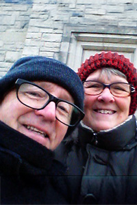 Clint and Karen, silver haired couple, hugging and smiling in beanie caps